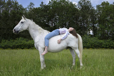 Junge Frau auf dem Rücken eines Pferdes liegend - PSTF00514