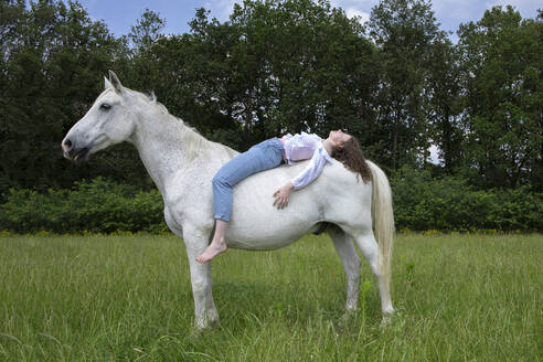 Young woman lying on back of a horse - PSTF00514
