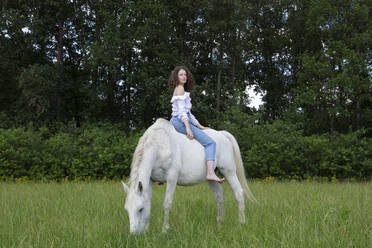 Junge Frau sitzt ohne Sattel auf einem Pferd - PSTF00523