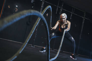 Blond sportswoman having workout with ropes - MADF01440