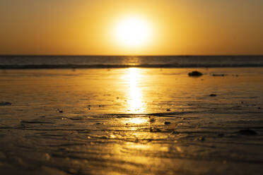 USA, California, Santa Monica, Setting sun illuminating wet sand of coastal beach - SEEF00071
