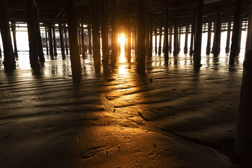 USA, Kalifornien, Santa Monica, Untergehende Sonne, die den Strandsand unter dem Santa Monica Pier beleuchtet - SEEF00074