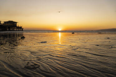 USA, Kalifornien, Santa Monica, Nasser Sand am Küstenstrand bei Sonnenuntergang mit Santa Monica Pier im Hintergrund - SEEF00076
