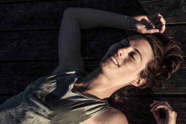 Portait of a happy woman lying on a jetty in sunlight - WFF00209