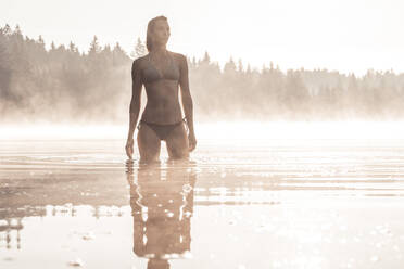 Frau im Bikini beim Baden in einem See im Morgennebel - WFF00210