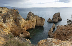 Portugal, Bezirk Faro, Lagos, Küstenklippen in der Morgendämmerung mit klarer Horizontlinie über dem Atlantischen Ozean im Hintergrund - FCF01845