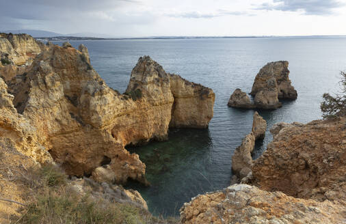 Portugal, Faro District, Lagos, Coastal cliffs at dawn with clear line of horizon over Atlantic Ocean in background - FCF01845