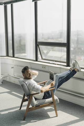 Älterer Geschäftsmann mit Laptop in leerem Büro, lizenzfreies Stockfoto