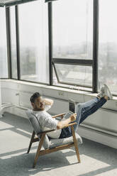 Mature businessman using laptop in empty office - KNSF06888