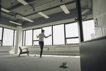 Mature businessman practicing yoga in empty office - KNSF06907