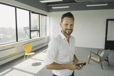 Portrait of confident mature businessman in empty office - KNSF06913