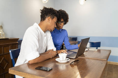 Studenten benutzen einen Laptop für ein Projekt in einem Cafe, lizenzfreies Stockfoto