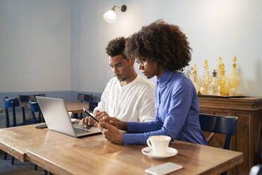 Schüler verwenden Laptop und Tablet für ein Projekt in einem Café - FBAF01052