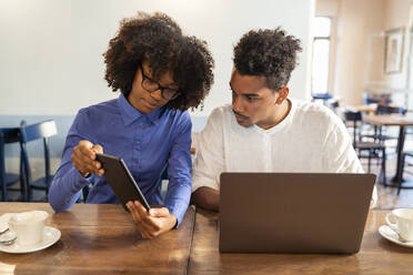 Schüler verwenden Laptop und Tablet für ein Projekt in einem Café - FBAF01054