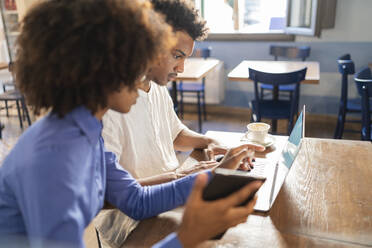 Students using laptop for a project in a cafe - FBAF01056