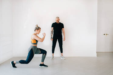 Fitness-Trainerin beobachtet Frau bei Ausfallschritten im Studio - ISF23165