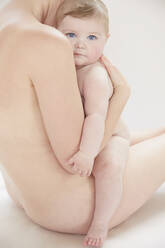 Nackte Mutter tröstet nacktes Baby, das an ihrer Brust ruht - ISF23220