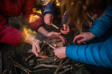Gruppe von Freunden beim Anzünden eines Lagerfeuers in der Abenddämmerung, Ausschnitt, Tofino, Vancouver Island, Kanada - ISF23234