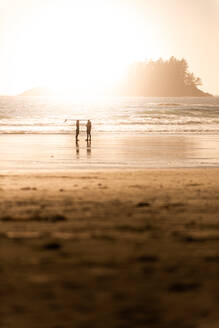 Silhouettenansicht von zwei Surfern am Strand bei Sonnenuntergang, Tofino, Vancouver Island, Kanada - ISF23235