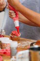 Handdekoration eines Cupcakes mit rotem Zuckerguss - ISF23242