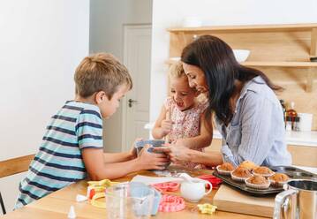 Mutter und Kinder backen Muffins in der Küche - ISF23257