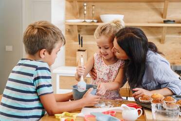 Mutter und Kinder backen Muffins in der Küche - ISF23258