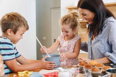 Mutter und Kinder backen Muffins in der Küche - ISF23264