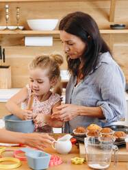 Mutter und Kinder backen Muffins in der Küche - ISF23269