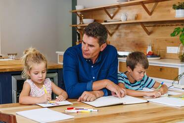 Vater hilft Kindern bei den Hausaufgaben zu Hause - ISF23298