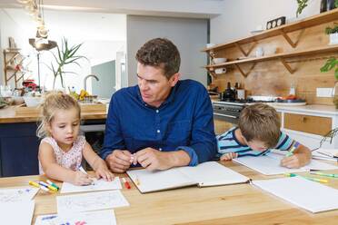 Vater hilft Kindern bei den Hausaufgaben zu Hause - ISF23329