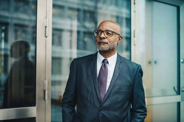 Confident thoughtful businessman wearing suit looking away at office - MASF15042