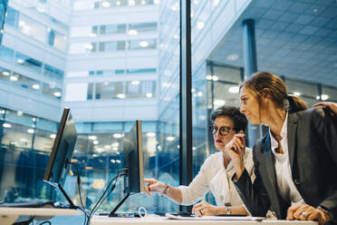 Geschäftsfrauen, die bei der Arbeit im Büro auf den Computer schauen und diskutieren - MASF15055