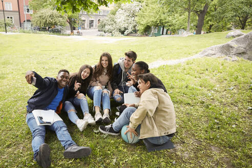 Hoher Winkel Blick auf fröhliche Freunde nehmen Selfie beim Sitzen im Park - MASF15137