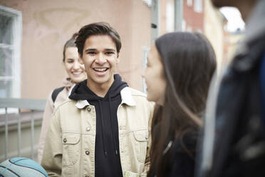Porträt eines lächelnden jungen Mannes, der mit seinen Freunden in der Stadt steht - MASF15151