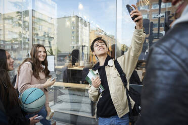 Lächelnde Freunde, die ein Selfie machen, während sie in der Stadt stehen - MASF15176