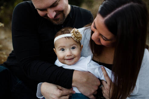 Mama & Papa umarmen Baby als Baby lächelt in die Kamera - CAVF69903