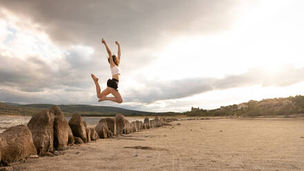 Mädchen springt glücklich am Meer - CAVF69913