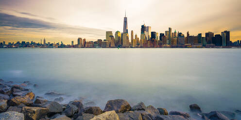 Skyline von Manhattan mit glattem Wasser und Steinen im Vordergrund - CAVF69917