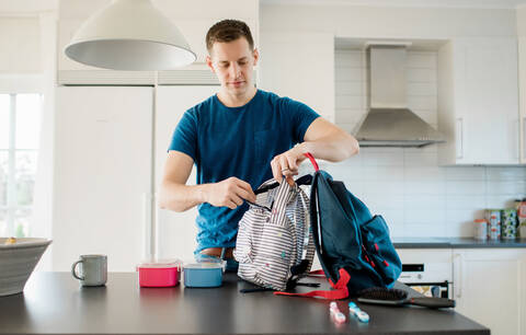 Father packing his kids school bags in the morning at home stock photo