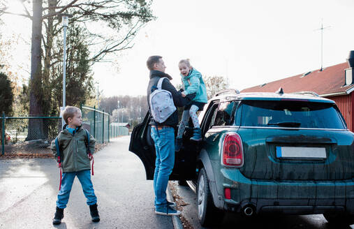 Ein Vater, der seine Kinder morgens in die Schule bringt - CAVF69969