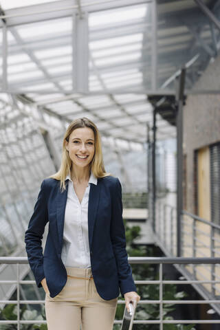 Porträt einer lächelnden jungen Geschäftsfrau in einem modernen Bürogebäude, lizenzfreies Stockfoto