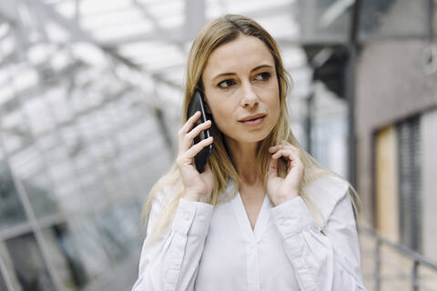 Porträt einer ernsten jungen Geschäftsfrau am Telefon, lizenzfreies Stockfoto