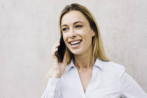 Porträt einer glücklichen jungen Geschäftsfrau am Telefon - JOSF03845