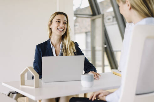 Two happy young businesswomen talking in office - JOSF03854