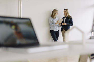 Two young businesswomen with tablet talking in office - JOSF03858