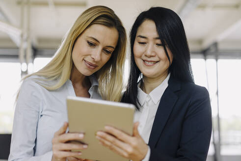 Zwei Geschäftsfrauen teilen sich ein Tablet im Büro - JOSF03890