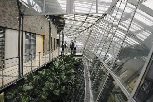 Geschäftsleute stehen auf einem Skywalk in einem modernen Bürogebäude - JOSF03906
