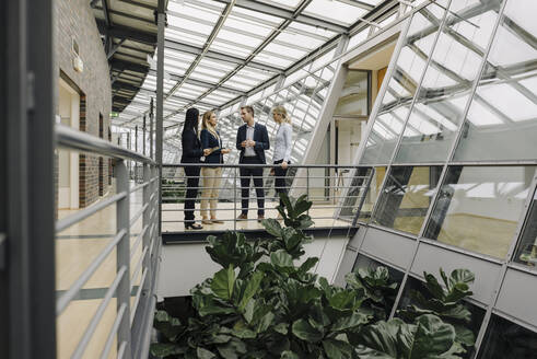 Geschäftsleute stehen auf einem Skywalk in einem modernen Bürogebäude - JOSF03907