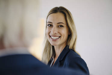 Portrait of a smiling young businesswoman in office with a colleague - JOSF03914