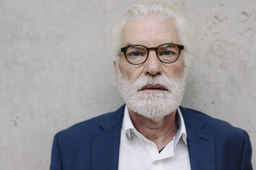 Portrait of serious senior businessman at a concrete wall - JOSF03935